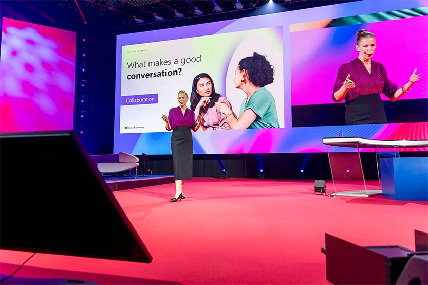 Tor Thompson presents on stage at DMEXCO 2025 with a large screen displaying the text “What makes a good conversation?” during her session on zero UI and conversational marketing.