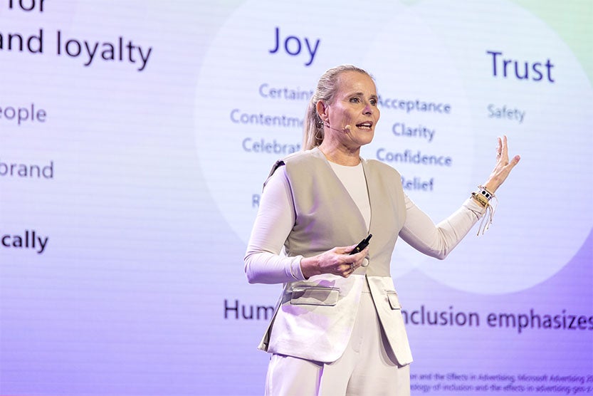 Mascha Driessen delivers a talk on personalized advertising at DMEXCO 2025, with a background screen highlighting key concepts like joy, trust, and loyalty in marketing.