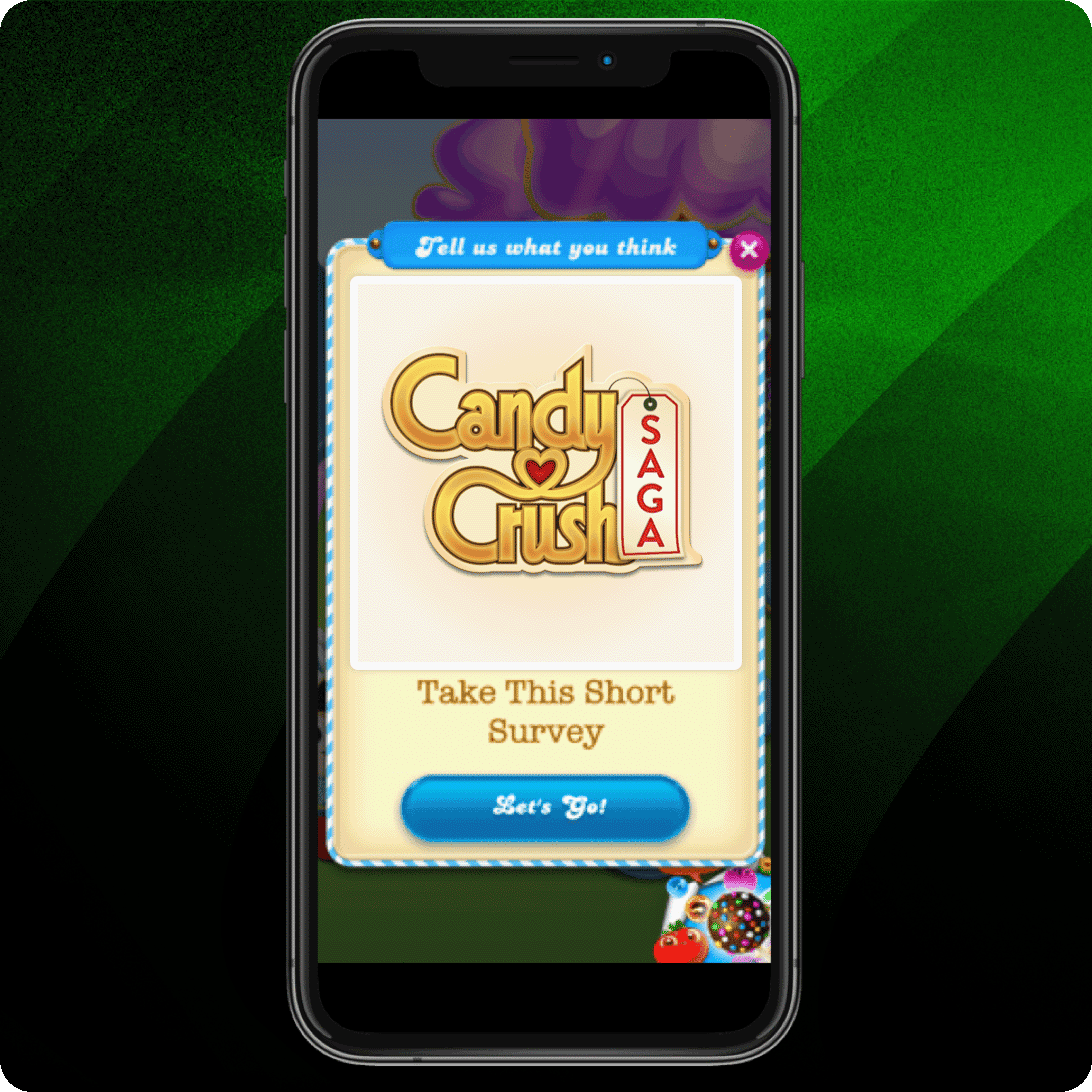 Smartphone mit Candy Crush Saga und einer Einladung zur Teilnahme an einer kurzen Umfrage vor einem grünen Farbverlauf.