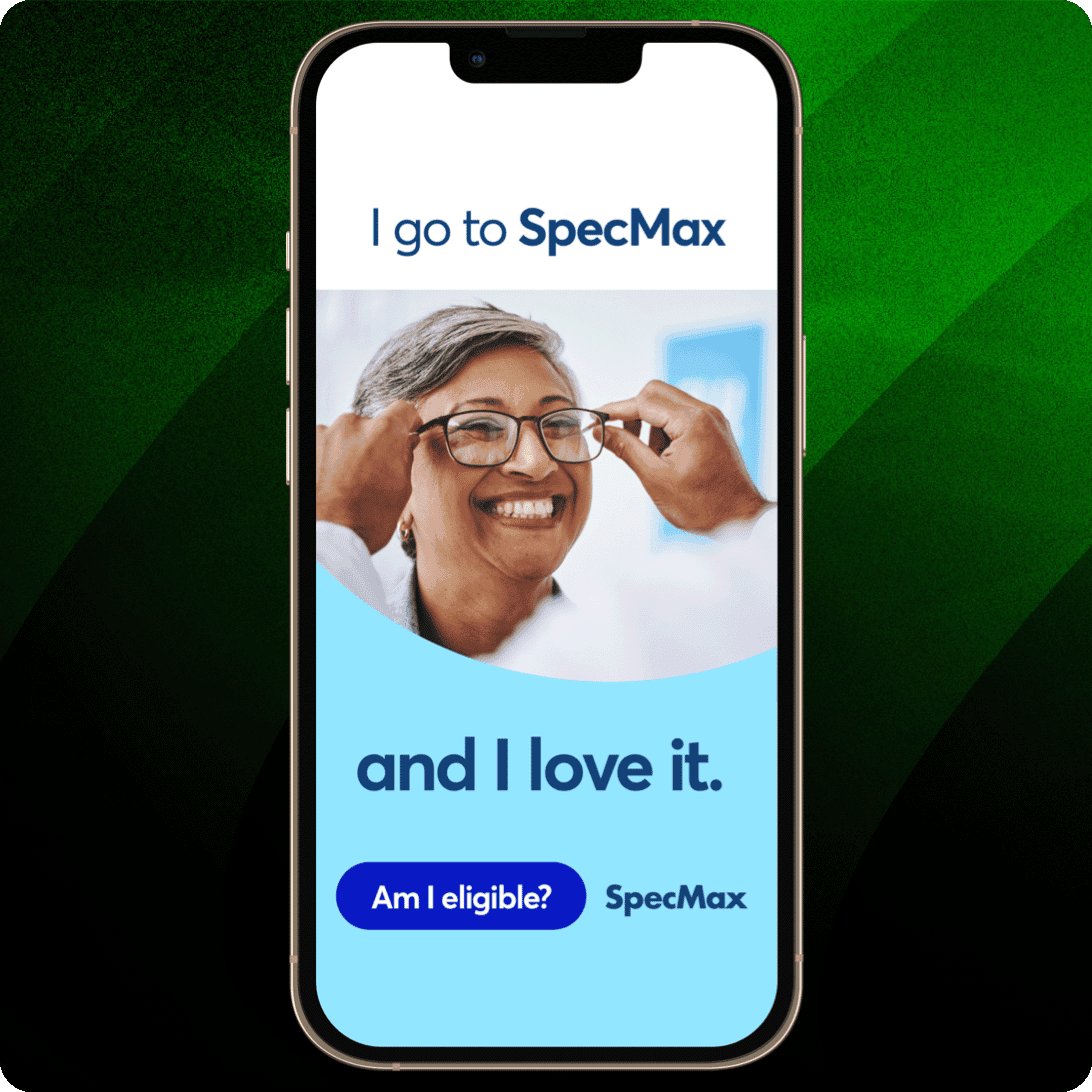 Smartphone displaying a SpecMax ad with a close-up image of a woman trying on glasses at a doctor’s office. Text around the image says “I go to SpecMax and I love it” with a button that says “Am I eligible?” 