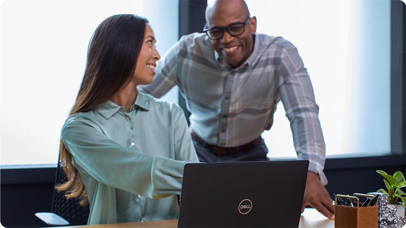 Two colleagues smiling and working together at an office space.