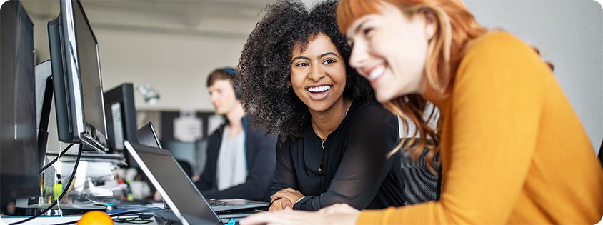 Two women colleagues in front of a computer in an office